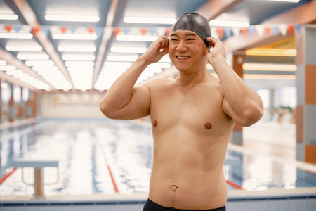 Asian man standing in indoors swimming pool and wearing a hatの写真素材