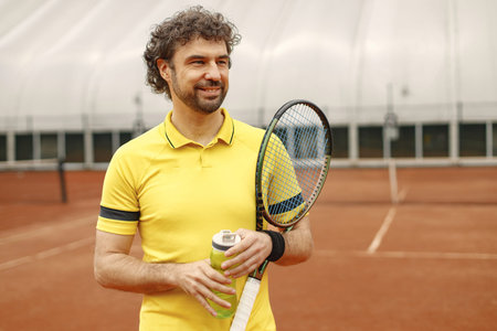 Portrait of tennis player standing in court with a racquet in his hands
