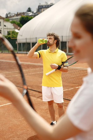 Male tennis player standing in court and woman standing in frontの写真素材
