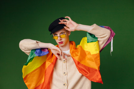Studio photo of a man with rainbow flag isolated on green backgroundの写真素材