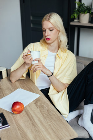 Blonde man with make up on his face sitting at the table in officeの写真素材