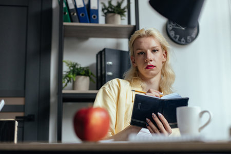 Blonde man with make up on his face sitting at the table in office
