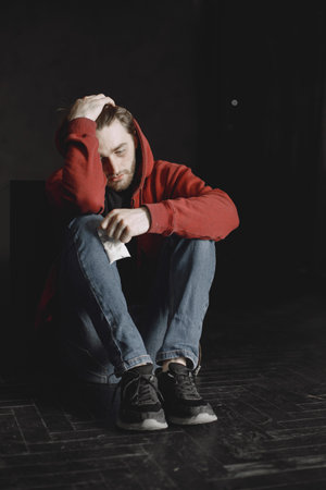 Young addicted man with cocain packet sitting aloneの写真素材