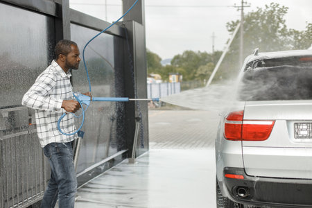 Middle aged black man cleaning his car outside in the car washの写真素材