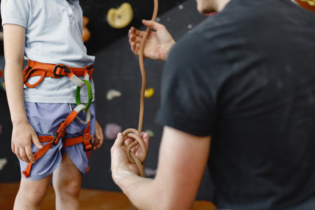 Midsection of a girl at climbing wall with male instructor in climbing centerの写真素材