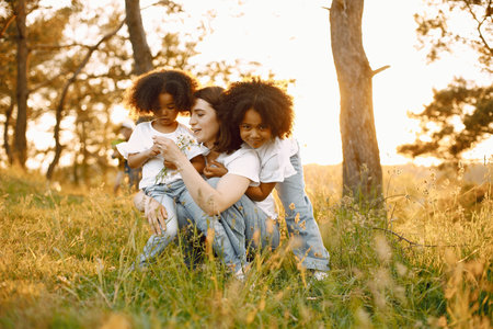 Caucasian mother embracing her two mixed race daughters in a sunsetの写真素材