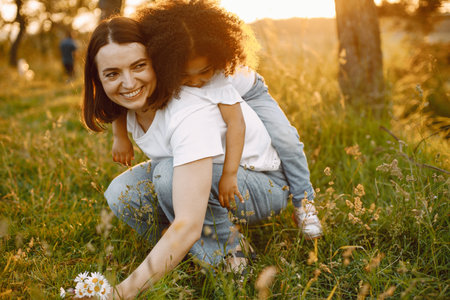 Caucasian mother holding her mixed race daughter on her backの写真素材