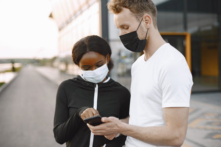 African-american woman and caucasian man looking at the phone while trainingの写真素材