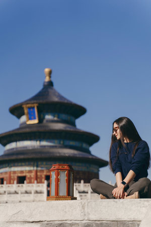 brunette girl sitting on the steps by temple of heaven in Chinaの写真素材
