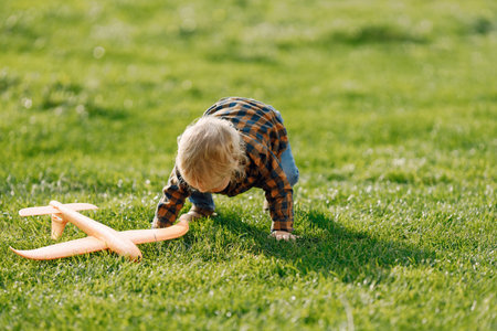 Blonde curly boy playing with a plane toy oudoorの写真素材