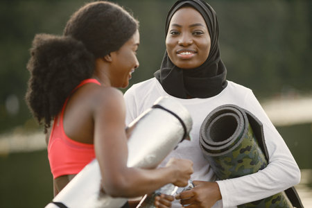 Muslim woman in hijab talking with her female friend after doing workoutの写真素材
