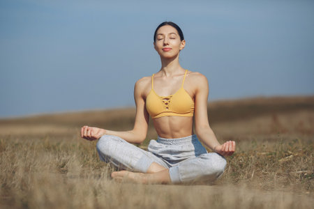 Cute girl training yoga on a sky backgroundの写真素材