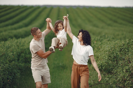 Family with little daughter spending time together in sunny fieldの写真素材
