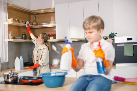 Little boy and his mother doing cleaning in a kitchen using a detergentsの写真素材