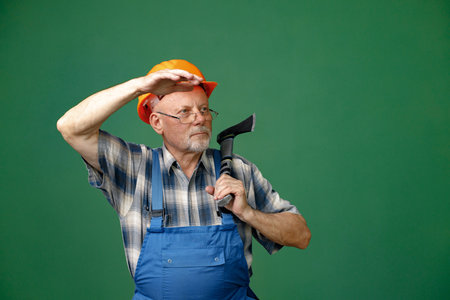 Studio photo of a man worker holding ax isolated on green backgroundの写真素材