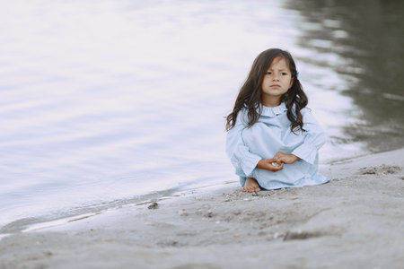Adorable curly baby girl splashing in a riverの写真素材