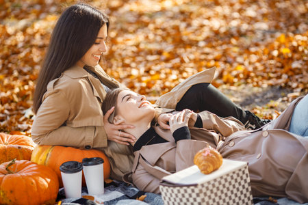 Two girls making picnic on a blanket in autumn parkの写真素材