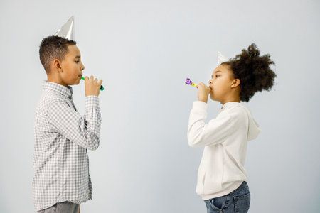 Multiracial boy and girl in birthday cap holding gift boxesの写真素材
