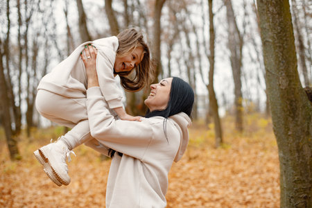 Mother with her daughter playing in autumn forestの写真素材