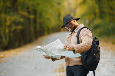 Black man standing on a road and holding a map