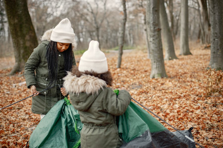 Two little black sisters in tent camping in the autumn forestの写真素材