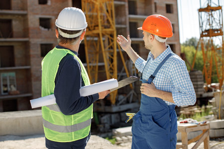 Two men engineers at a construction site are looking at the drawings