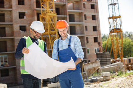 Two men engineers at a construction site are looking at the drawings
