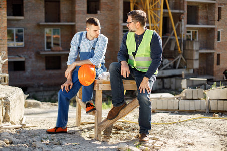 Two men engineers at a construction site are talking