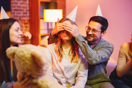 Friends sitting on a sofa in a cozy room and celebrating birthdayの写真素材