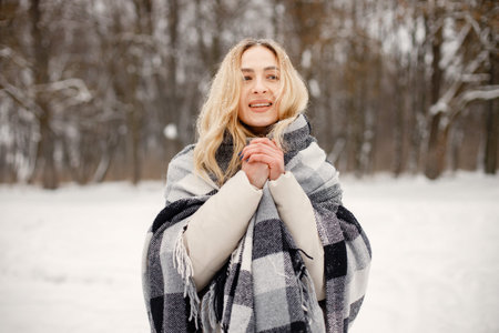 Portrait of a woman standing in winter forest and posing for a photo