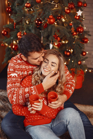 Cute couple sitting at home near christmas treeの写真素材