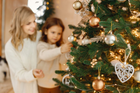 Little girl and her mom having fun near Christmas tree togetherの写真素材