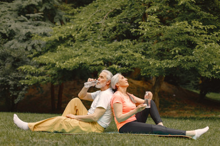 Senior couple sitting on exercise mats at park and restingの写真素材