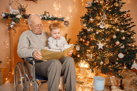 Little boy and his old grandfather on a wheelchair sitting near Christmas treeの写真素材