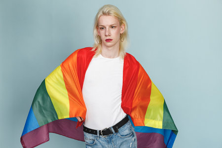Studio photo of a fashionable man with make up isolated on blue backgroundの写真素材