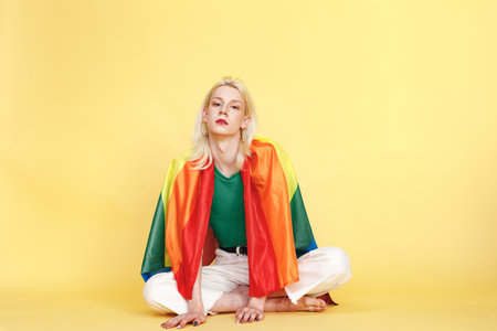 Studio photo of a fashionable man with make up isolated on yellow backgroundの写真素材