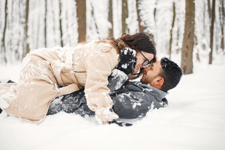 Portrait of a romantic couple lay in snow in winter forestの写真素材