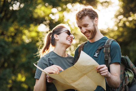 Young couple standing in forest at summer with a mapの写真素材