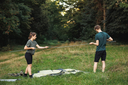Young couple setting up a tent in forest at summerの写真素材
