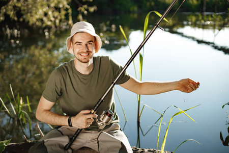 Young fisherman with fishing rod near the lake at summer