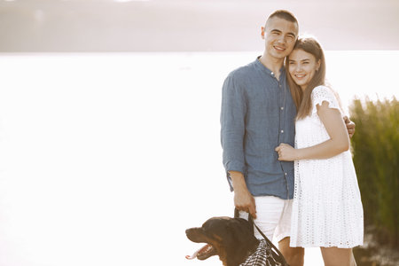 Portrait of a romantic couple with their rotweiller near the lakeの写真素材