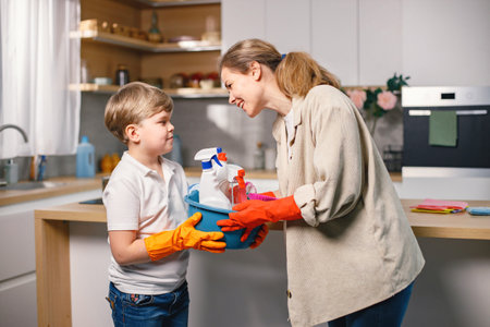 Little boy and his mother cleaning in a kitchen using a detergentsの写真素材