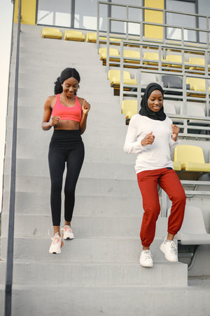 Two black women running down a stairs on a stadiumの写真素材