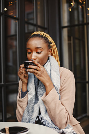 African woman in a brown coat sitting outsideの写真素材
