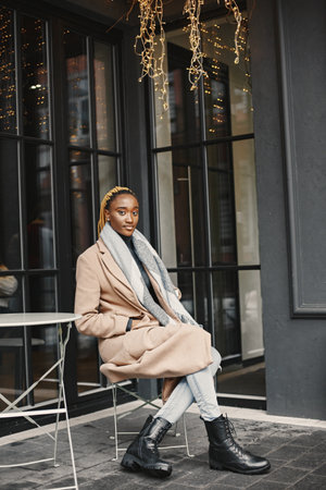 African woman in a brown coat sitting outsideの写真素材