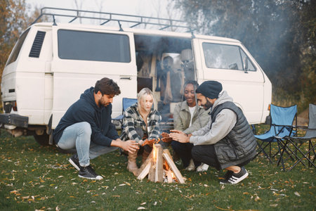 Young friends warming hands by fire at forestの写真素材