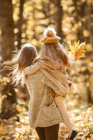 Mother and her daughter playing and having fun in autumn forestの写真素材