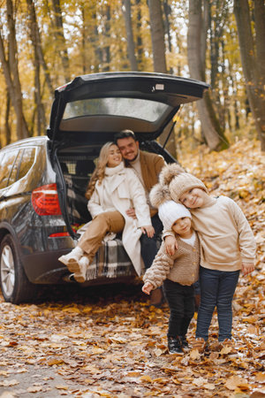 Young family sitting at open trunk of hatchback car in autumn forestの写真素材