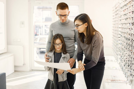Optometrist helping family choosing glasses in optics store