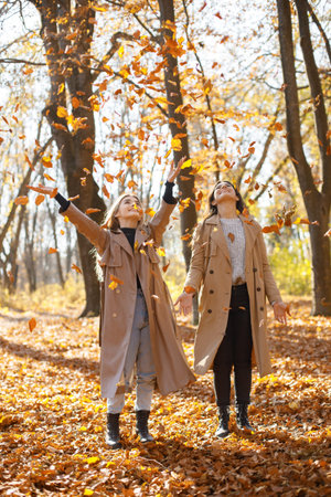 Two girls friends spending time together in autumn park